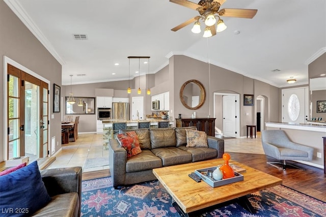 living room with arched walkways, visible vents, lofted ceiling, and ornamental molding