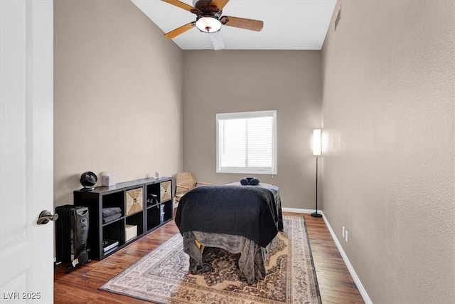 bedroom featuring a ceiling fan, wood finished floors, visible vents, and baseboards