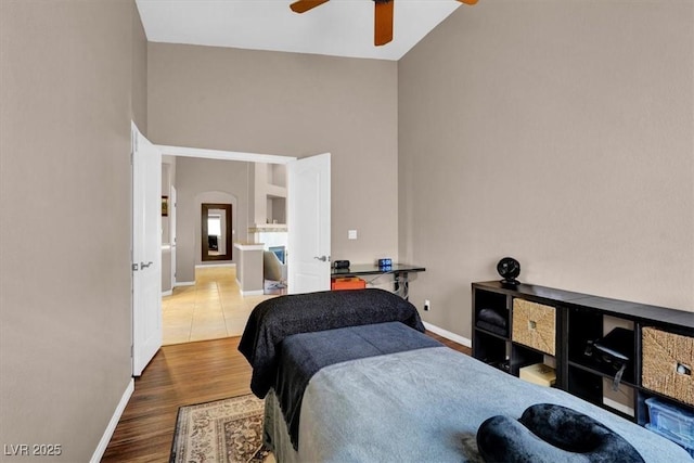 bedroom featuring a high ceiling, wood finished floors, arched walkways, and baseboards