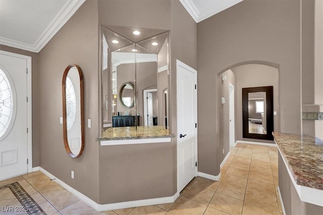 entrance foyer featuring arched walkways, ornamental molding, and light tile patterned flooring