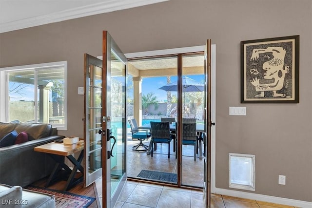 doorway featuring light tile patterned flooring, french doors, crown molding, and baseboards