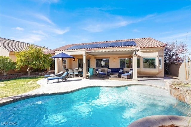 rear view of property featuring a tile roof, roof mounted solar panels, stucco siding, an outdoor hangout area, and a fenced backyard