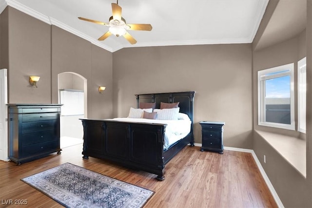 bedroom featuring crown molding, baseboards, wood finished floors, arched walkways, and a ceiling fan