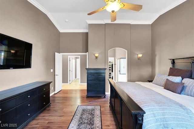 bedroom featuring dark wood finished floors, crown molding, arched walkways, and ceiling fan