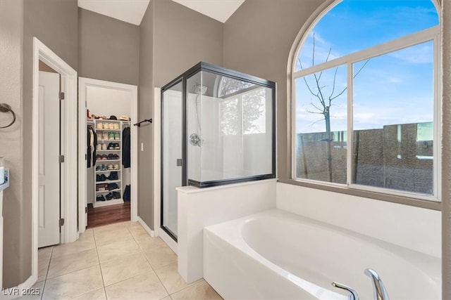 bathroom featuring tile patterned flooring, a stall shower, a bath, and a walk in closet