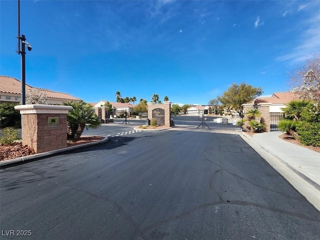 view of road with a gate, sidewalks, curbs, a gated entry, and a residential view