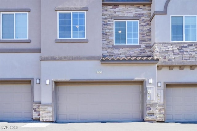 view of front facade featuring stone siding, stucco siding, and an attached garage