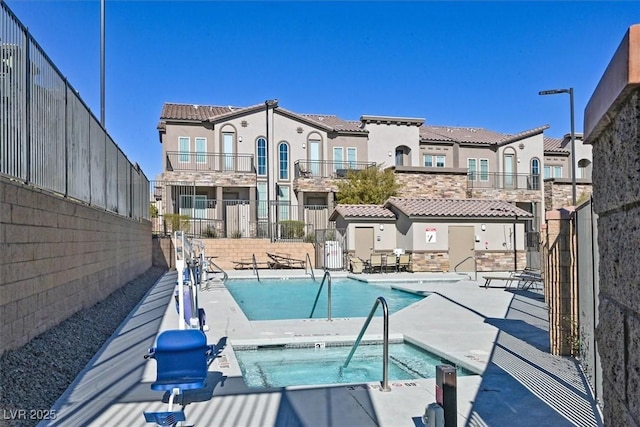 pool featuring a community hot tub, a patio, and fence