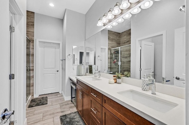 full bath featuring double vanity, baseboards, a stall shower, and a sink