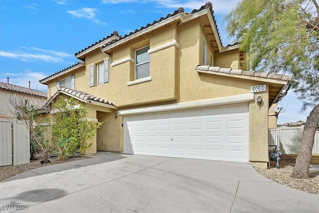 view of front of property featuring fence, a tile roof, concrete driveway, stucco siding, and an attached garage