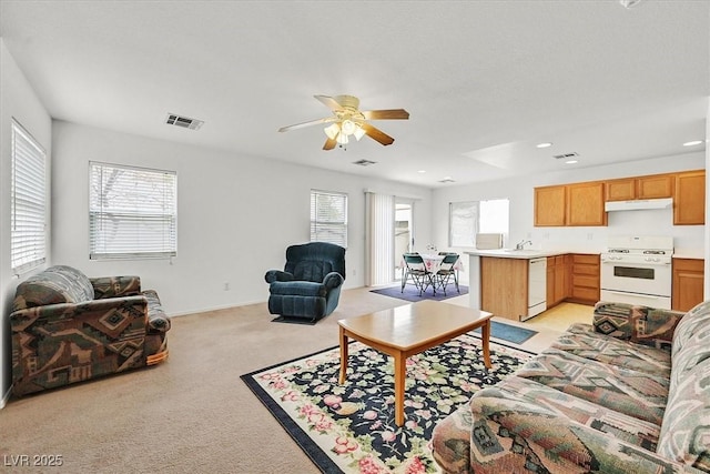 living room with visible vents, light colored carpet, and a ceiling fan