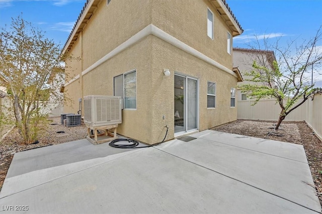 rear view of house featuring a patio area, central AC unit, stucco siding, and a fenced backyard