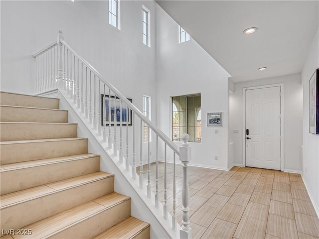 entryway featuring stairs, recessed lighting, a healthy amount of sunlight, and baseboards