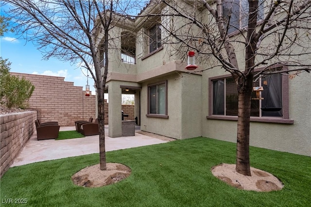 rear view of property with a patio area, stucco siding, a lawn, and a balcony