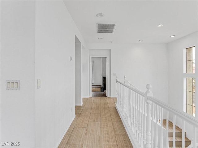 hallway with an upstairs landing, visible vents, recessed lighting, and baseboards