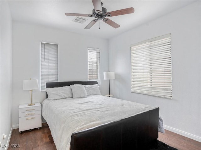 bedroom with visible vents, wood finished floors, baseboards, and ceiling fan