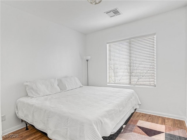 bedroom featuring visible vents, baseboards, and wood finished floors