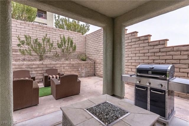 view of patio with area for grilling, a fire pit, and fence