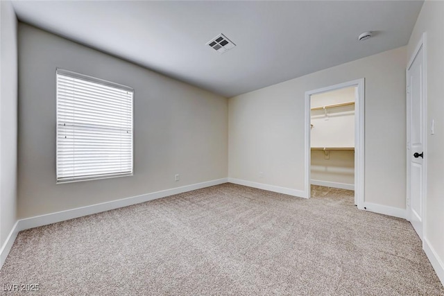 unfurnished bedroom with visible vents, a walk in closet, baseboards, carpet, and a closet