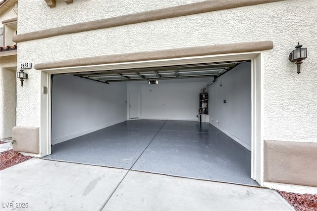 garage featuring strapped water heater, concrete driveway, and a garage door opener