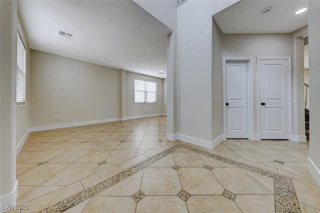 unfurnished room featuring light tile patterned flooring, visible vents, and baseboards