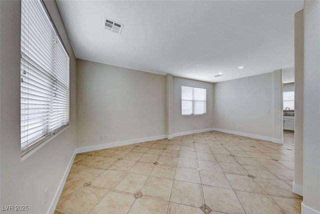 spare room with light tile patterned floors, visible vents, baseboards, and a sink