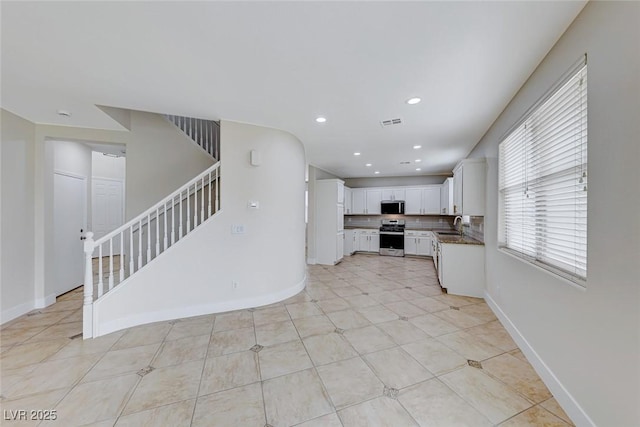 kitchen with appliances with stainless steel finishes, white cabinetry, and baseboards