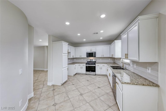 kitchen featuring light stone counters, appliances with stainless steel finishes, tasteful backsplash, and a sink