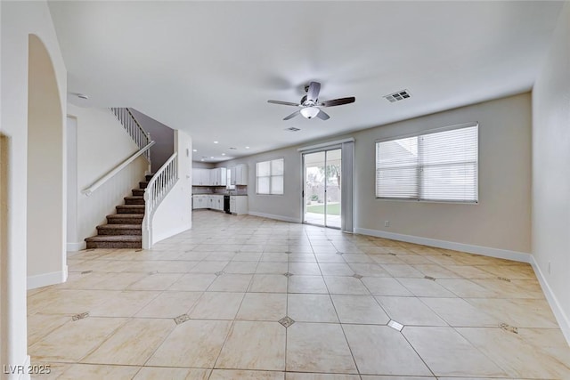 unfurnished living room featuring a ceiling fan, visible vents, and baseboards