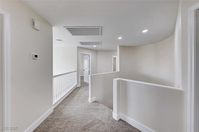 hallway featuring an upstairs landing, visible vents, carpet flooring, and baseboards