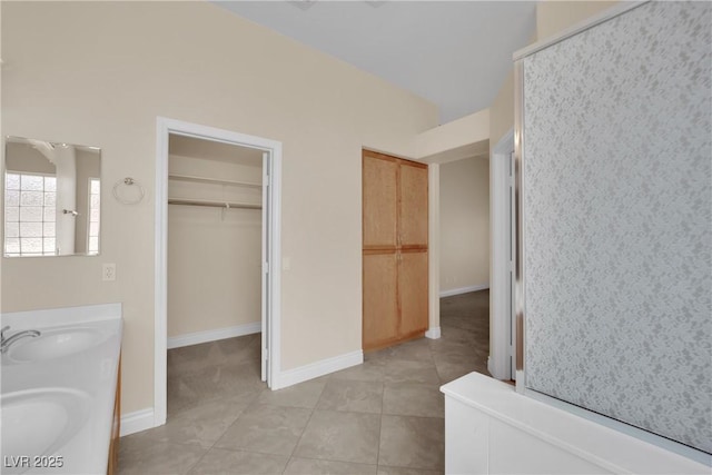 full bath featuring tile patterned floors, a spacious closet, baseboards, and a sink