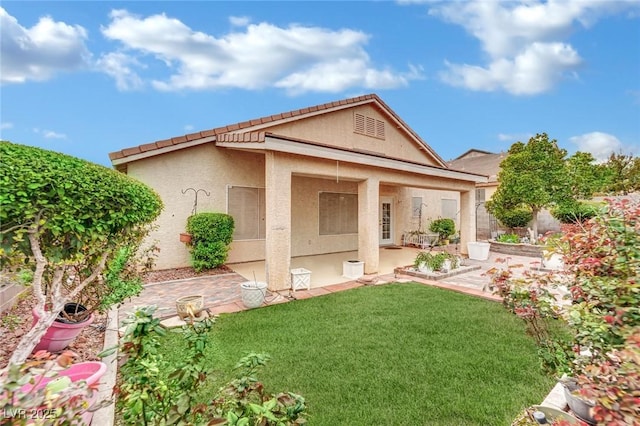 rear view of property featuring stucco siding, a lawn, and a patio