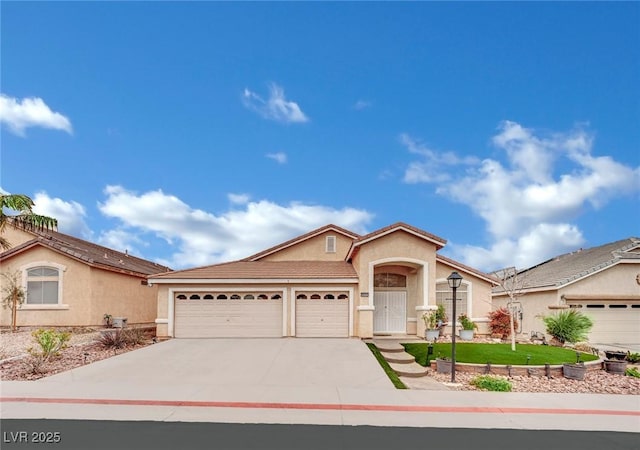 view of front facade featuring a tiled roof, an attached garage, driveway, and stucco siding