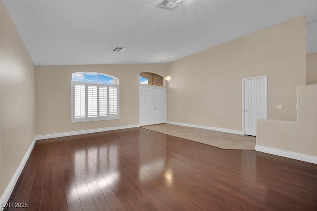 empty room featuring visible vents, wood finished floors, and vaulted ceiling