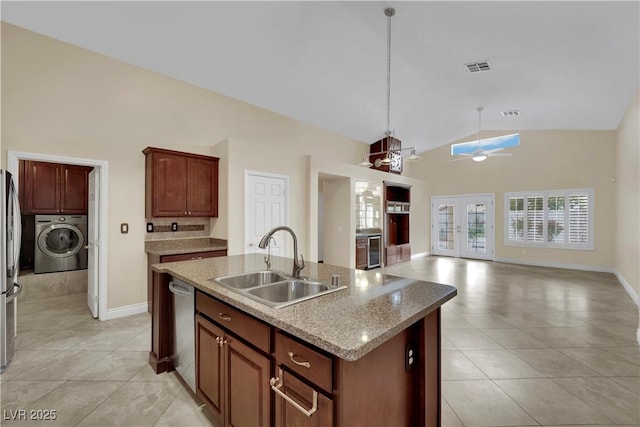 kitchen featuring a center island with sink, visible vents, washer / dryer, stainless steel appliances, and a sink