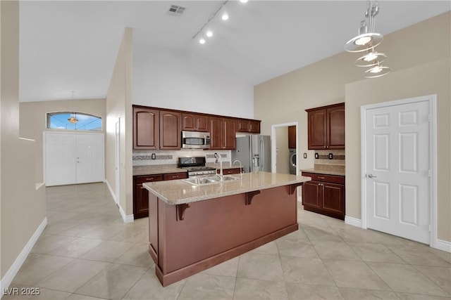 kitchen featuring visible vents, a breakfast bar, a kitchen island with sink, a sink, and stainless steel appliances