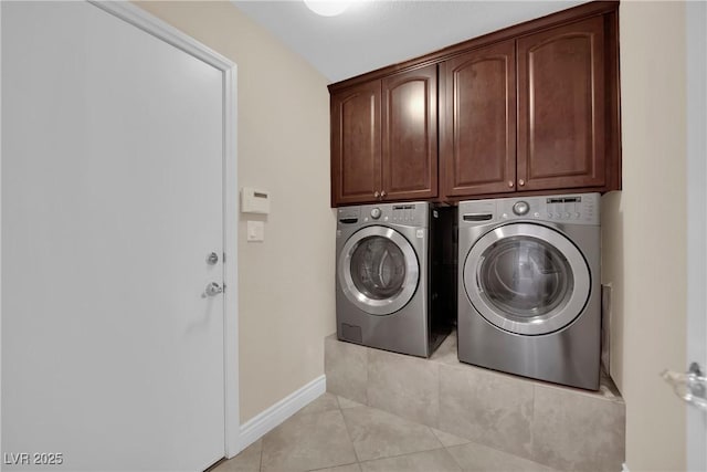 clothes washing area featuring washer and clothes dryer, light tile patterned floors, cabinet space, and baseboards