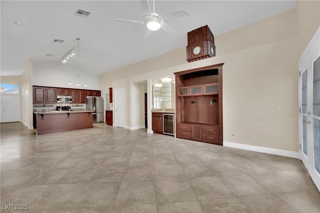 unfurnished living room with visible vents, wine cooler, baseboards, and a ceiling fan