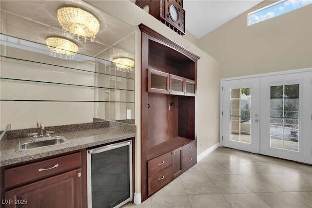 interior space featuring beverage cooler, light tile patterned floors, indoor wet bar, french doors, and a sink