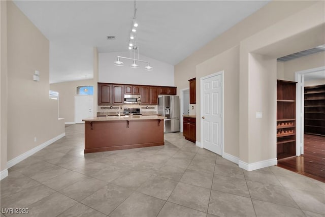 kitchen with baseboards, decorative light fixtures, a kitchen bar, light countertops, and stainless steel appliances