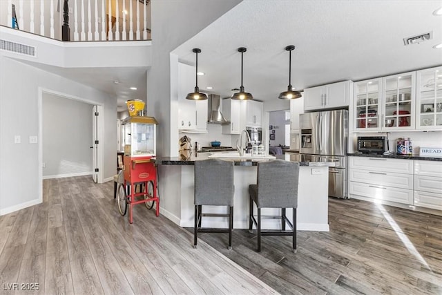8433 Honeywood Cir, Las Vegas, NV 89128 - kitchen with stainless steel appliances, wall chimney range hood, wood finished floors, white cabinets, and recessed lighting