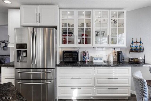 8433 Honeywood Cir, Las Vegas, NV 89128 - kitchen featuring stainless steel refrigerator with ice dispenser, glass insert cabinets, white cabinets, dark stone counters, and recessed lighting