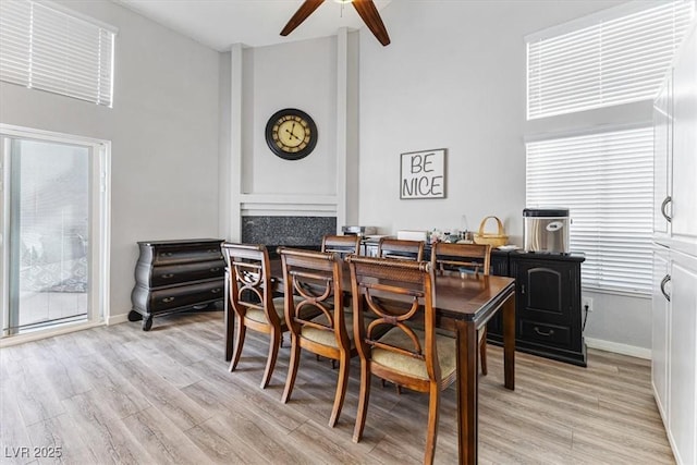 8433 Honeywood Cir, Las Vegas, NV 89128 - dining room featuring a towering ceiling, a ceiling fan, light wood-style floors, and baseboards