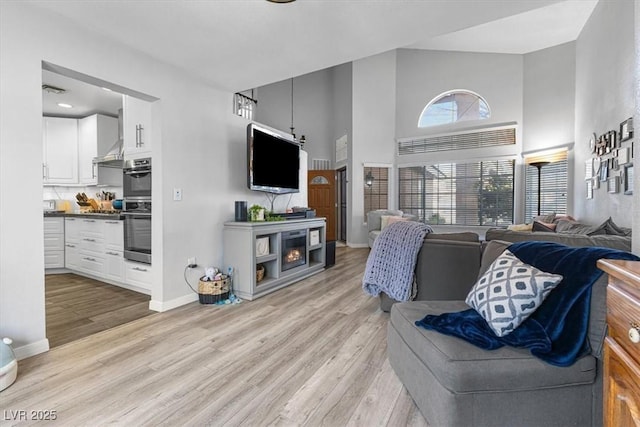 8433 Honeywood Cir, Las Vegas, NV 89128 - living area featuring light wood-style flooring, a towering ceiling, and baseboards
