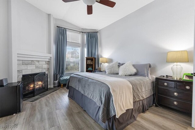 8433 Honeywood Cir, Las Vegas, NV 89128 - bedroom featuring lofted ceiling, wood finished floors, a stone fireplace, and ceiling fan