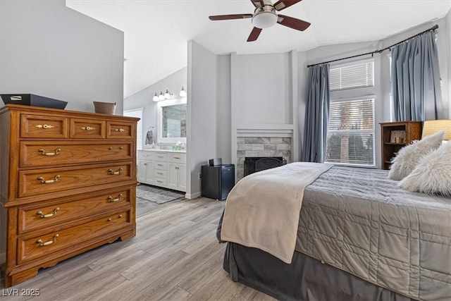 8433 Honeywood Cir, Las Vegas, NV 89128 - bedroom with lofted ceiling, light wood-style flooring, a stone fireplace, ensuite bath, and a ceiling fan