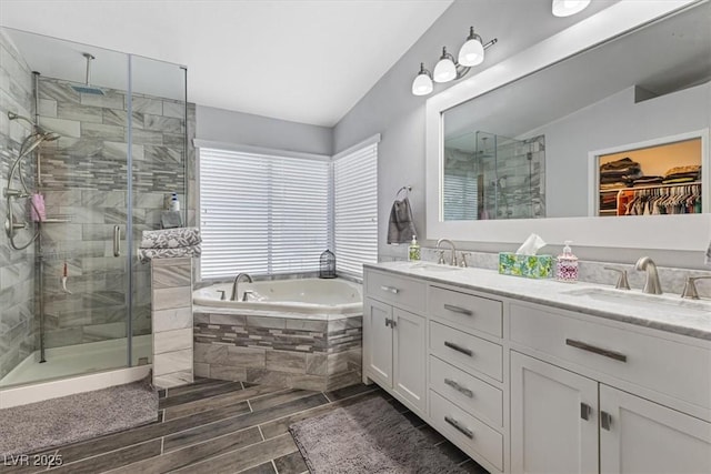 8433 Honeywood Cir, Las Vegas, NV 89128 - bathroom featuring a shower stall, double vanity, a bath, vaulted ceiling, and wood finish floors
