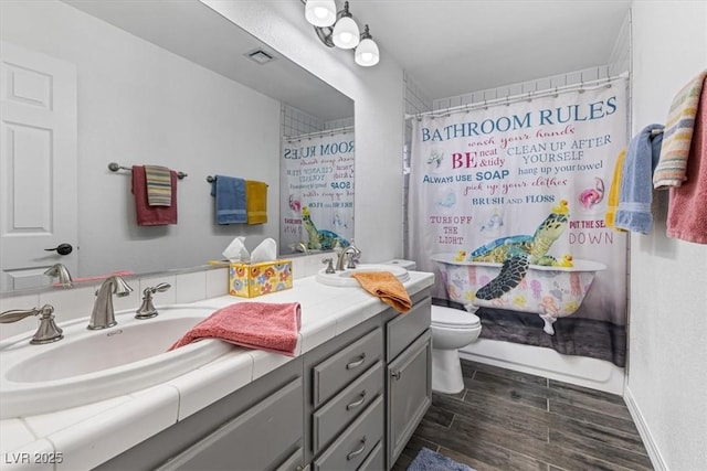 8433 Honeywood Cir, Las Vegas, NV 89128 - full bathroom featuring double vanity, toilet, wood finished floors, a shower with shower curtain, and baseboards