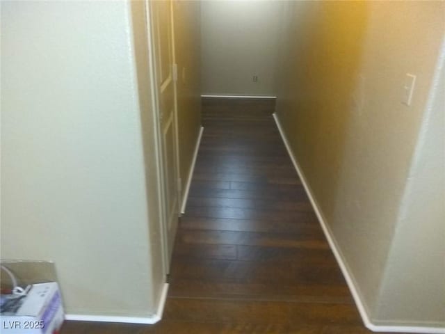 hallway with dark wood finished floors and baseboards