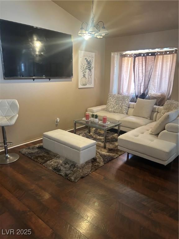 living area featuring vaulted ceiling, an inviting chandelier, and wood finished floors